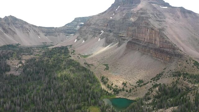 Aerial View of Secluded Amethyst Lake in Valley Under Peaks of Uinta Mountains. Picturesque Landscape and Pine Forest in Utah USA. Drone Shot