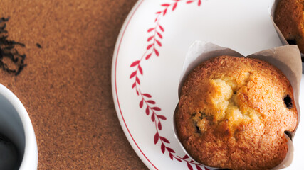 Tiempo de relajarse tomarse un momento y disfrutar de un delicioso Muffin de arándanos junto a una rica taza de café caliente. Vista en cenital de taza de cerámica junto a Muffin casero.