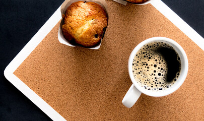 Tiempo de relajarse tomarse un momento y disfrutar de un delicioso Muffin de arándanos junto a una rica taza de café caliente. Vista en cenital de taza de cerámica junto a Muffin casero.