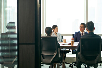 group of asian corporate executives discussing business in conference room