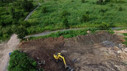 Close fly over tracked excavator clearing land in rural SE Asia