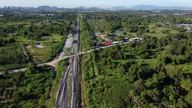 Fly high over train line and unmanned level crossing in rural SE Asia