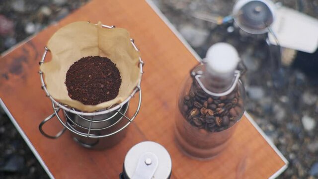キャンプ場でコーヒー豆を挽いてコーヒーを入れて飲む一人の男性