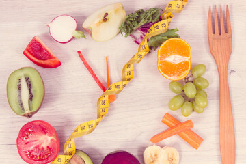 Tape measure with fruits and vegetables in shape of clock, healthy nutrition and slimming concept