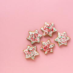 Homemade christmas gingerbread cookies in the shape of stars on a pink background, top view