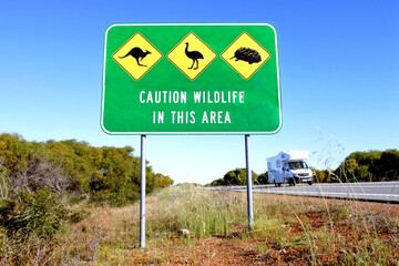 Motorhome passing by a large sign reading caution wildlife in the area