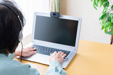 ウェブカメラを使用してオンライン通信をするシニア女性	