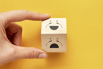 Image of a crying and laughing face on wooden cubes. The ultimate manifestation of emotions of joy and sorrow