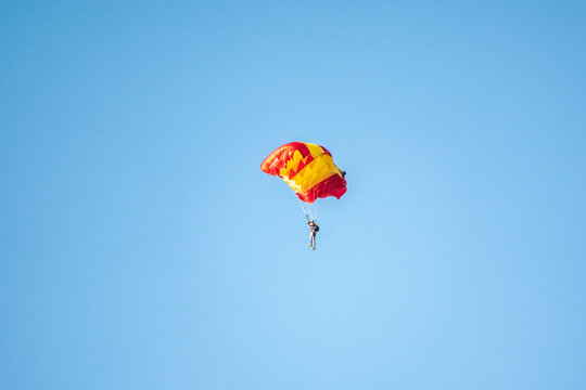 One parachutist floats slowly at low altitude on the background of clear sky