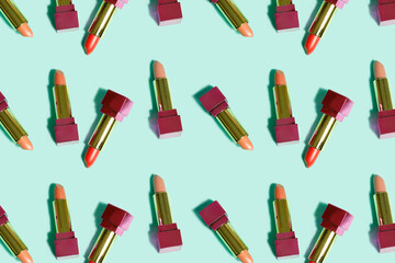 Makeup pattern Repeat rows of lipsticks of different colors on light green background. Top view of open tubes of lipstick. Horizontal. Cosmetics and beauty concept.