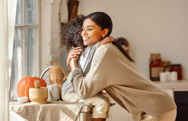 Happy ethnic family mother and   son hugging in the kitchen at home.