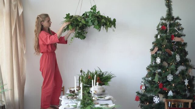 woman florist dressed in work overalls makes a festive wreath over the table