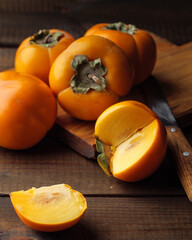 A slice of yellow persimmon on a wooden table. With a whole persimmon around.