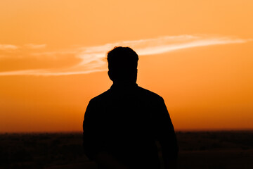Silhouette of an Indian business man standing in front of the sun during the sunset