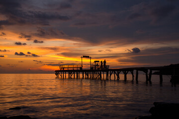 Obraz premium The scenery of the silhouette of the couple taking a photo on the wood bridge in sunset time in Koh Kood island, Trat province, Thailand.