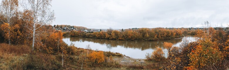 Beautiful panorama of autumn morning on the calm river with village on their bank. Panorama landscape.