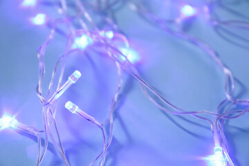 Glowing Christmas lights on color background