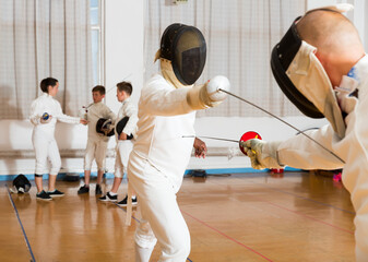 fencing duel with foils of two professional athletes in gym