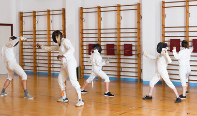 Ordinary group practicing effective fencing techniques in sparring in training room
