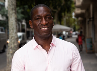 Fototapeta premium Portrait of cheerful African American enjoying walk through city in summer day