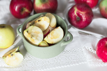 Apple slices in a green bowl on the table close-up. background with Apple slices and red apples on a napkin.