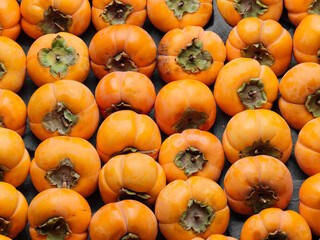 Lots of bright ripe persimmons in the box. Close-up. Seasonal autumn fruit. Top view. Close-up.