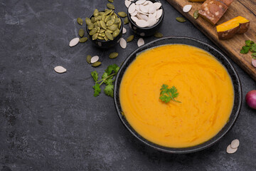 Curry or pumpkin soup with rice served in a ceramic platter on a black background - top view with writing space.