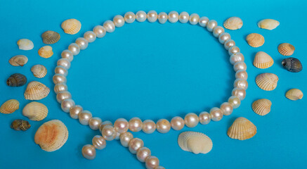 Marine layout. Pearl beads and lots of small shells on a blue background.