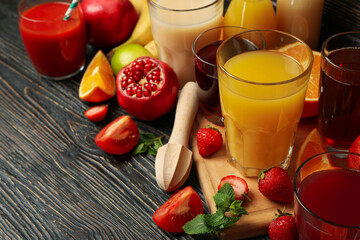 Glasses and jars with different juices on wooden background