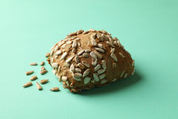 Bun with sunflower seeds on mint background