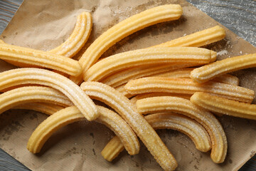 Baking paper with churros on wooden background