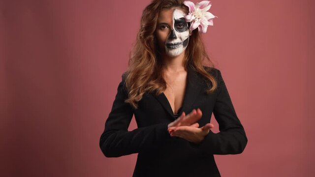 portrait of a woman in makeup for Halloween. Skull painted on the face. claps hands