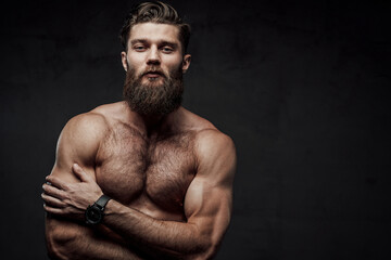 Naked man with muscular build and beard posing with crossed arms looking at camera in dark background. - Powered by Adobe
