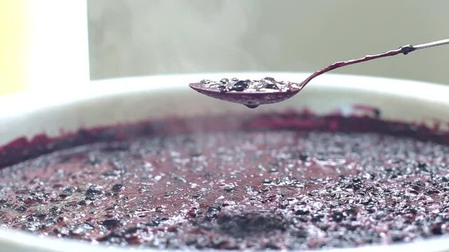 Stir with a spoonful of blueberry jam. Making jam from wild blueberries, jam