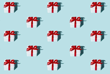 Gift pattern. Blue seamless background. Holiday surprise. Care package. Symmetrical arrangement of white boxes with red ribbon bows isolated on light.
