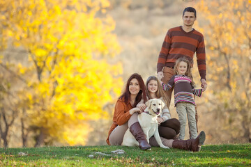 Fototapeta premium Family resting in nature in autumn. Beautiful woman with a man have fun playing with children. High quality photo.