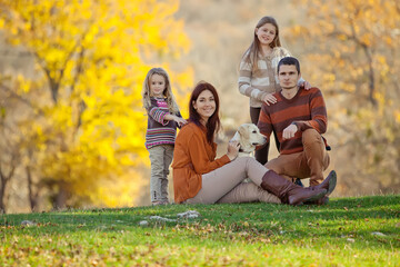 Fototapeta premium Family resting in nature in autumn. Beautiful woman with a man have fun playing with children. High quality photo.