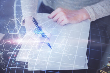 Multi exposure of hands making notes with world map hologram and data theme icons. Concept of global computer data.