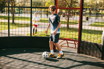 A young man in a sports uniform trains with a ball on the freestyle football court. A football player plays with a ball. Sports, leisure, training, freestyle © Sviatlana