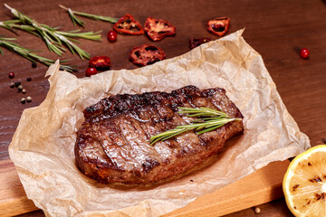 Marbled veal fried on charcoal with vegetables and spices on a wooden board. European cuisine.