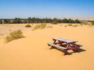 Fototapeta na wymiar a picnic table on desert sand dunes with blue sky 