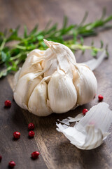 Garlic with red pepper and herbs on wooden background