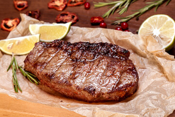 Marbled veal fried on charcoal with vegetables and spices on a wooden board. European cuisine.