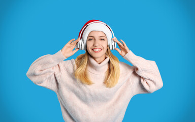 Happy woman with headphones on blue background. Christmas music