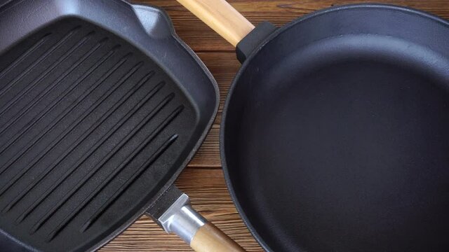 Two new non-stick cast iron pans on a wooden background. Grill pan with wooden handle, cooking accessories