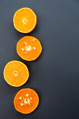 Citrus. Tangerines halves on black plates on a black background. Healthy food and vitamins