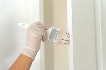 woman hand painting white door. 