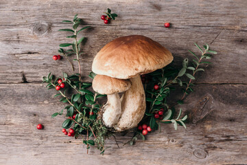 Red whortleberry and boletus edulis mushroom on wooden background. Copy space. Top view. Organic...