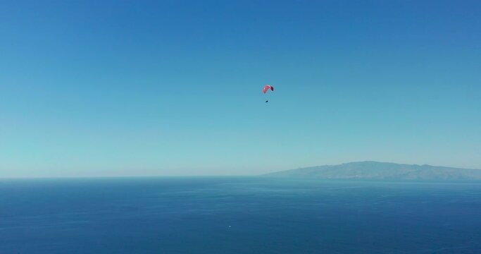 Extreme paraglider flying against a clear blue sky.