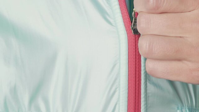 Woman athlete, close up fastens the lock of a sports jacket close up. A lock that fastens a woman's clothes. zipper jacket close up closes